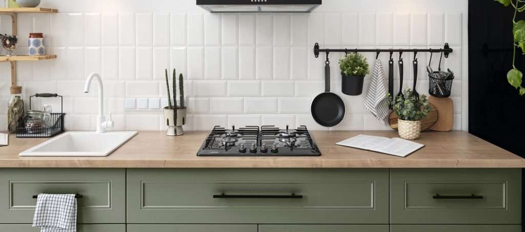 Moderne keuken met witte wandtegels, houten werkblad en groene keukenkastjes – stijlvolle en onderhoudsvriendelijke keukeninrichting.