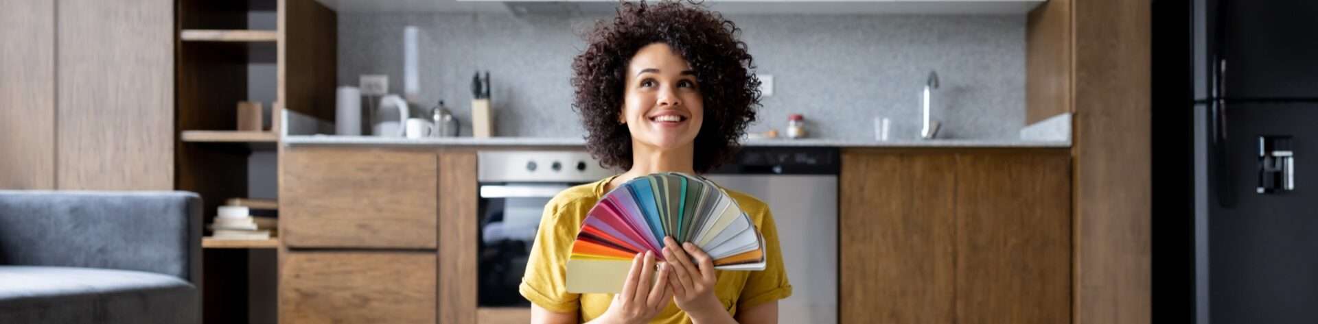 Vrouw met kleurstalen en kleurenwaaier kiest een nieuwe kleur voor keuken of interieur.