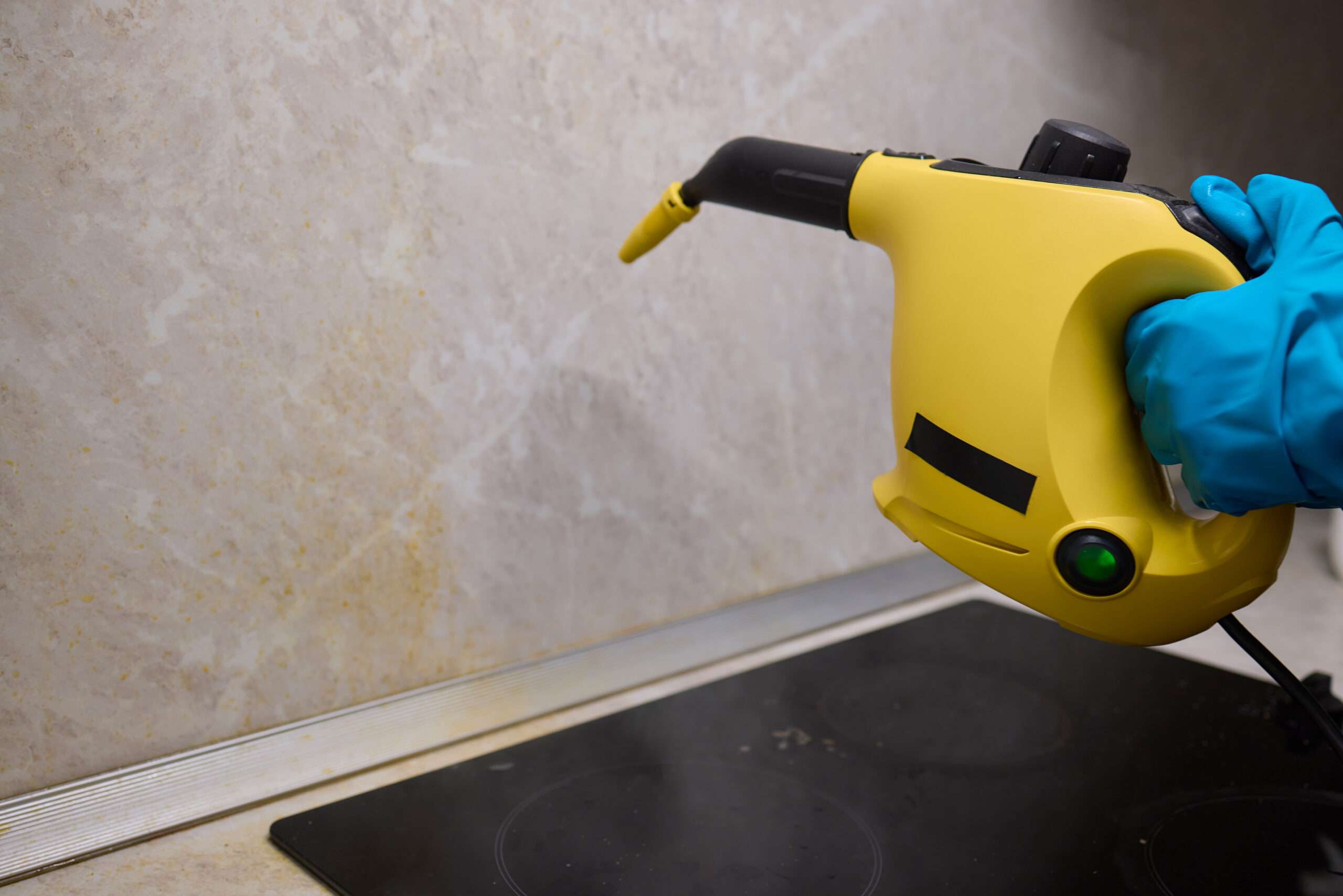 Hand die witte marmerlook tegels schoonmaakt met een gele doek – onderhoud badkamertegels, tips voor tegelreiniging, glanzende wandtegels schoonmaken voor hygiënische badkamer. Stoomreiniger wordt gebruikt om wandtegels schoon te maken – effectief tegels reinigen in keuken of badkamer, verwijdert vuil en bacteriën, hygiënische schoonmaak met stoom voor tegelonderhoud.