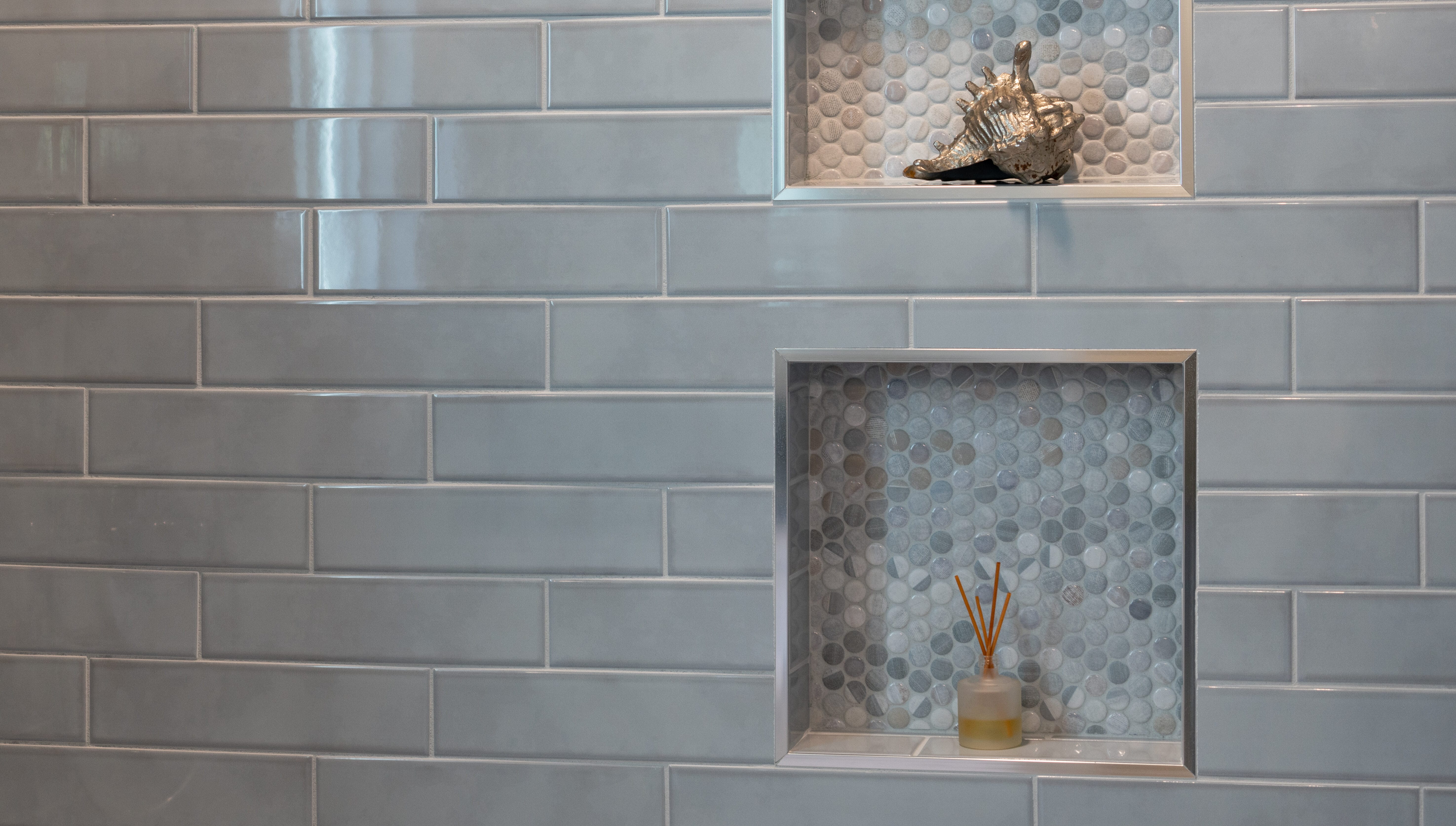 Lichtblauwe rechthoekige wandtegels in kwartsteensverband met nissen afgewerkt met mozaïek tegels in rond patroon, inspiratie voor badkamer wandtegels en creatieve nisafwerking