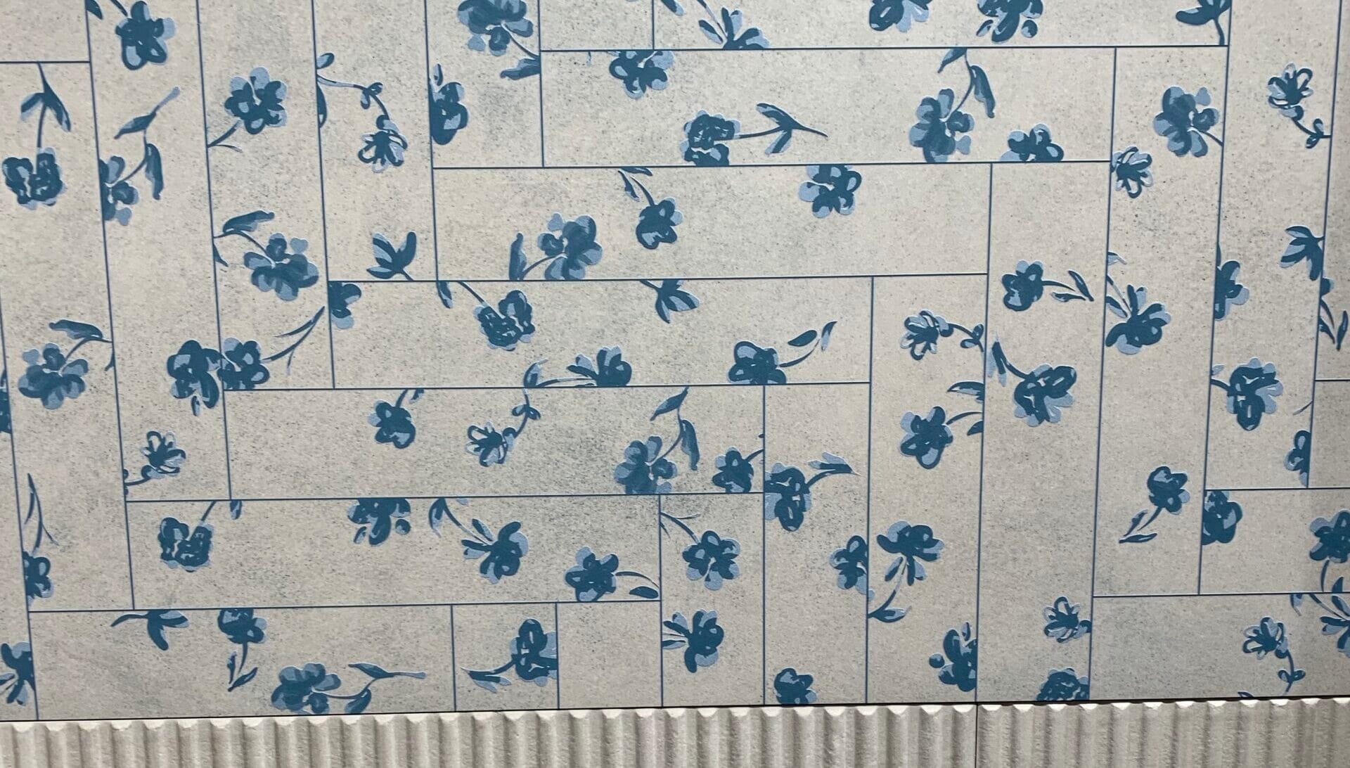 Wand met rechthoekige tegels in elleboogpatroon met blauw bloemendecor, inspiratie voor creatieve legpatronen en decoratieve wandtegels