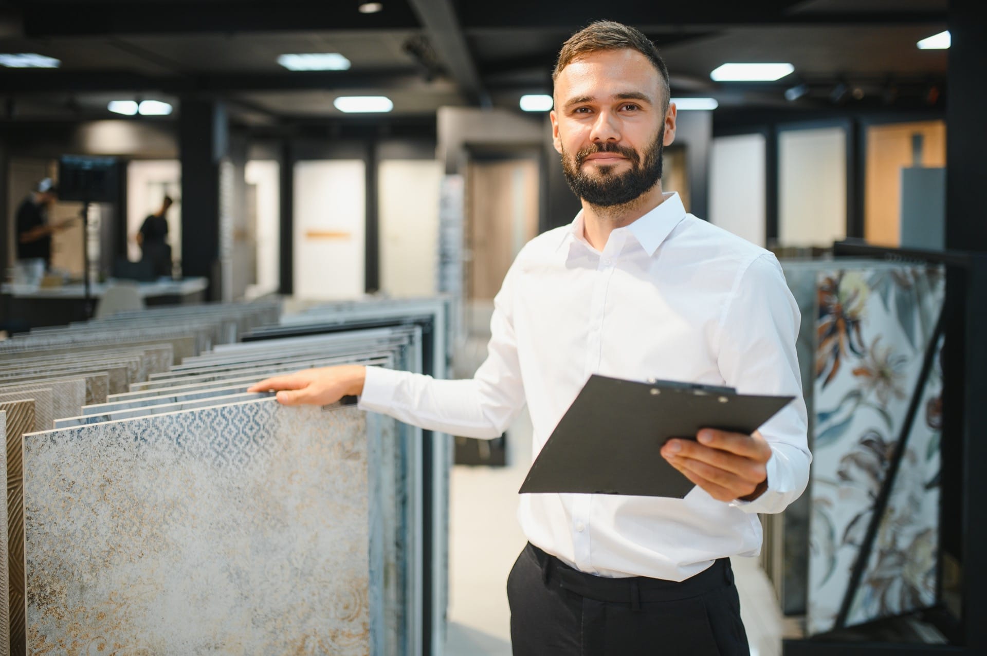 Vriendelijke medewerker in tegelwinkel adviseert over diverse tegels en tegelsoorten – persoonlijk advies en ruime keuze in tegels voor ieder interieur