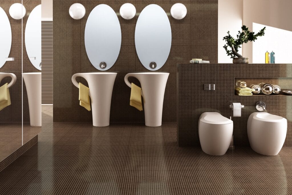 Moderne badkamer met kleine bruine mozaïektegels op vloer en wand, met ovale spiegels, vrijstaande waskommen en toilet. Strak design met accent op keramische tegels.