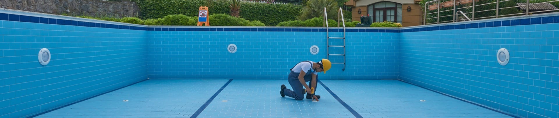 Werkman aan het werk in groot blauw zwembad